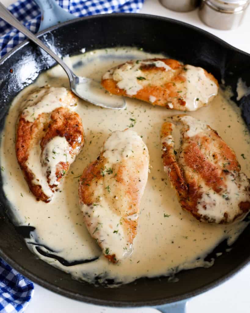 A large black skillet full of lightly battered pan-fried chicken in a ranch cream sauce. 