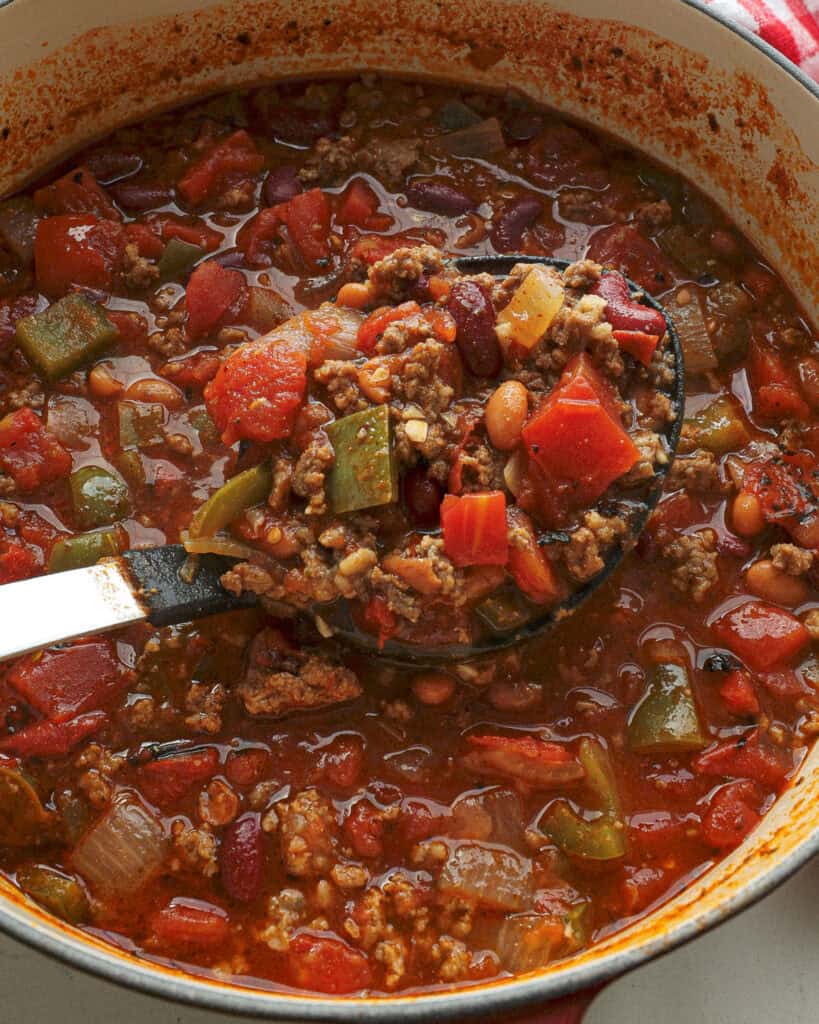 A Dutch oven full of beef chili with bell peppers, onions, garlic and tomatoes. 