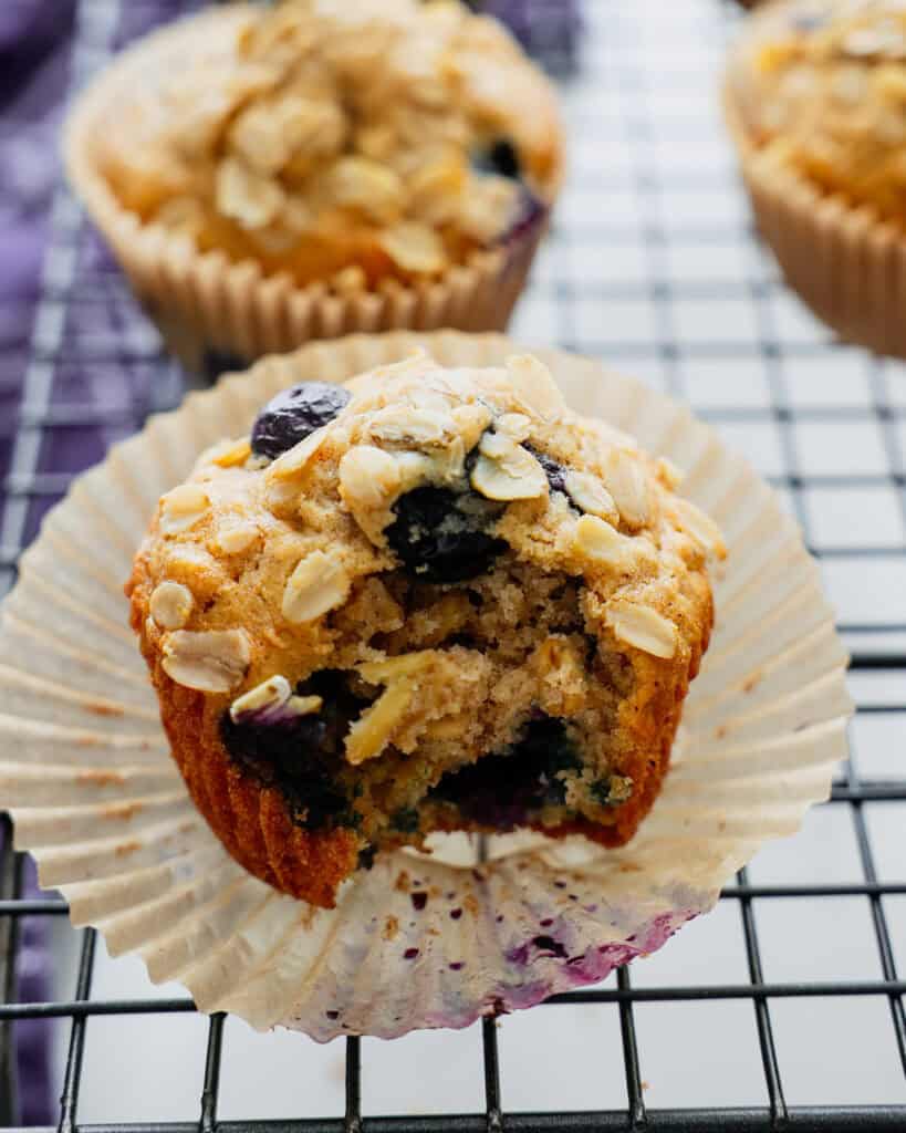 A close up view of a blueberry oatmeal muffin with a bite out of it. 