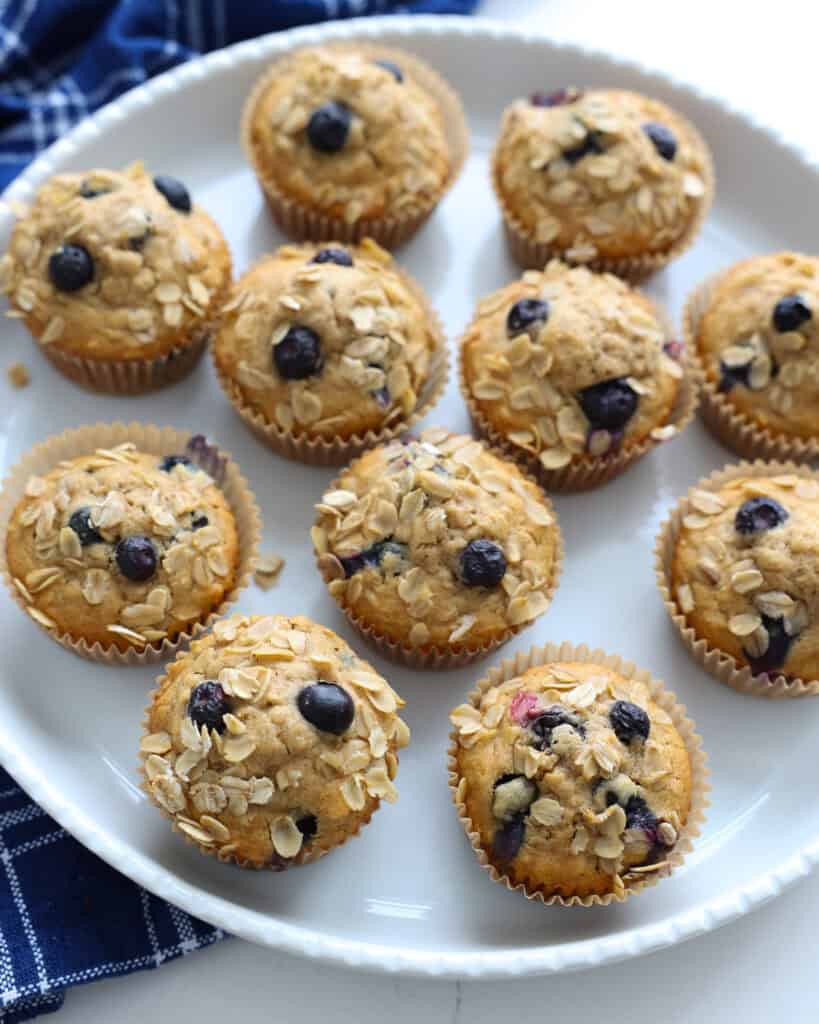 A round white serving platter full of oatmeal blueberry muffins. 
