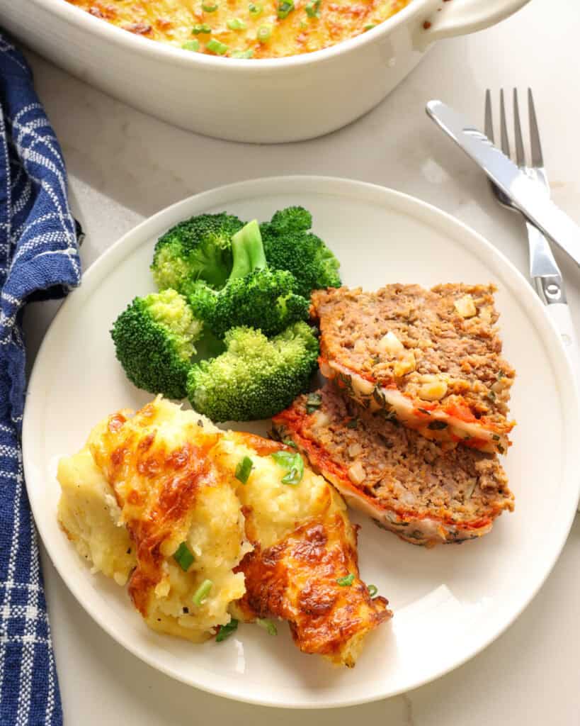 A single serving plate with cheesy mashed potatoes, Italian meatloaf, and steamed broccoli. 