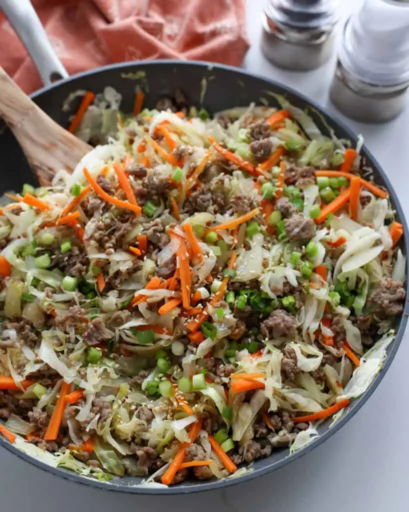 A close up view of a skillet full of egg roll in a bowl.