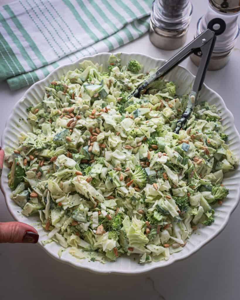 A serving bowl full of Green Goddess salad with a salt and pepper shaker in the background. 
