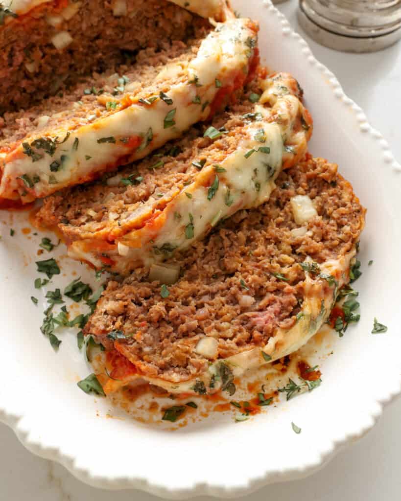 A close up view of Italian meatloaf on a white serving platter