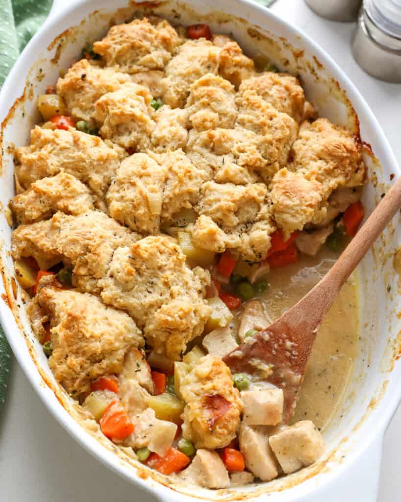 An overhead view of chicken cobbler with a wooden spoon in it. 
