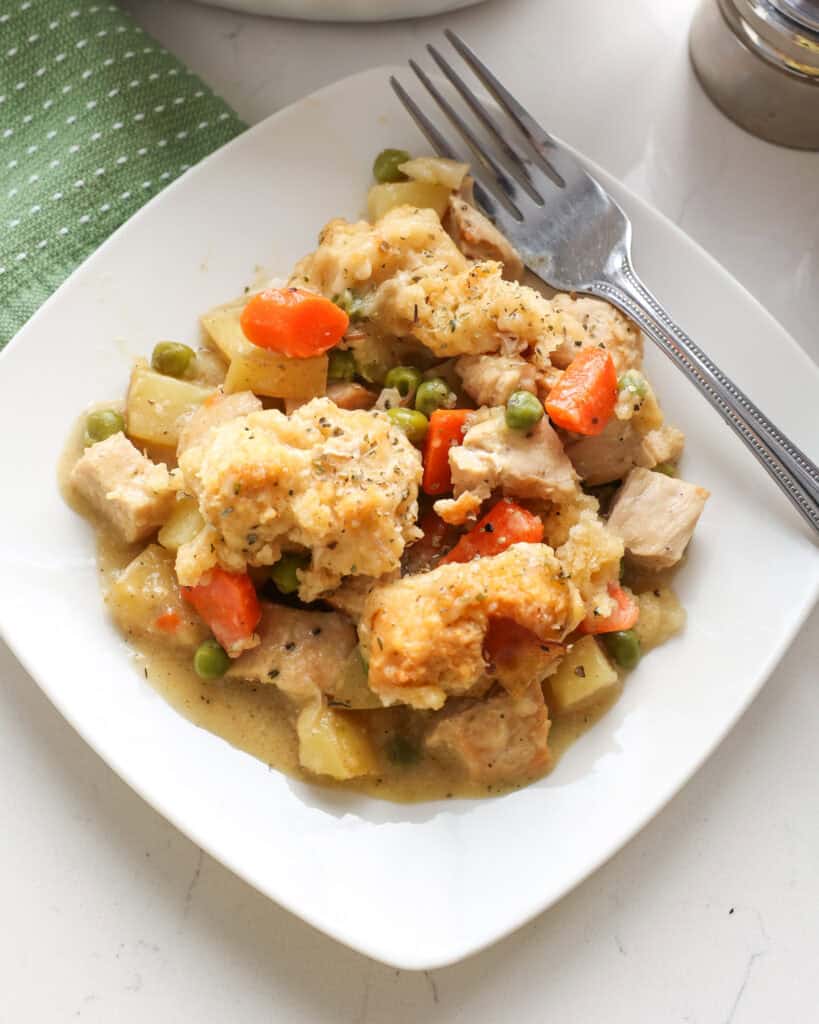 A single serving white plate full of chicken cobbler 