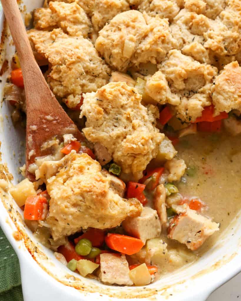 A close up view of chicken cobbler on a spoon in an oval casserole dish. 