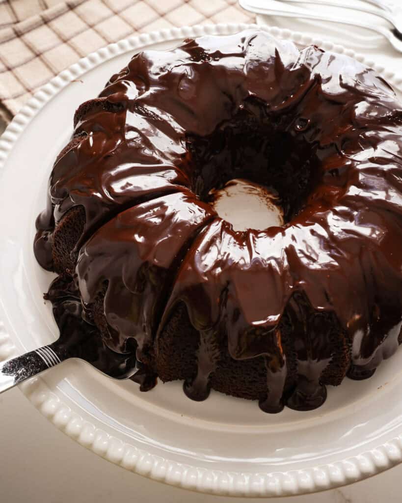 An over head view of a chocolate bundt cake with a slice cut out of it and on a cake server.