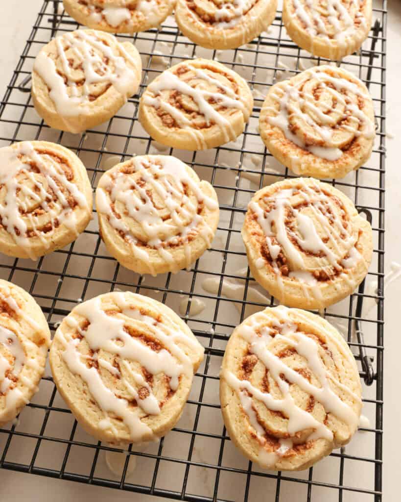 Iced cinnamon roll cookies on a wire rack. 