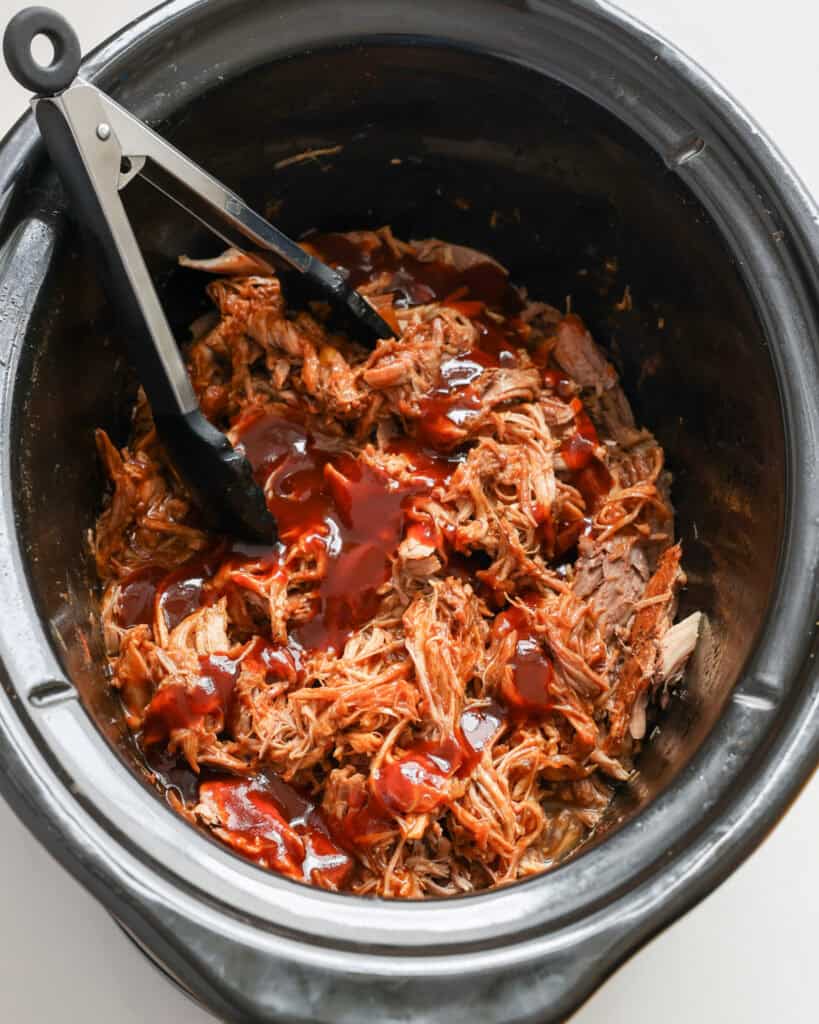 A overhead view of Dr Pepper Pulled Pork in a black crock pot. 