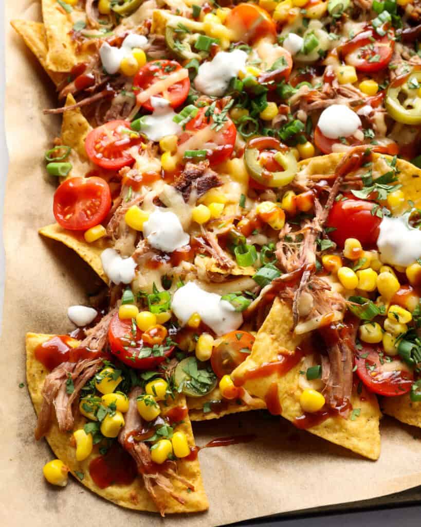 Pork nachos on a baking sheet covered with parchment paper. 