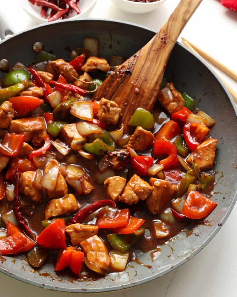 An overhead view of Szechuan chicken with red chilis. 