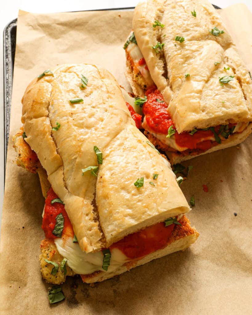 Chicken parmesan sandwich on a baking sheet covered with parchment paper. 