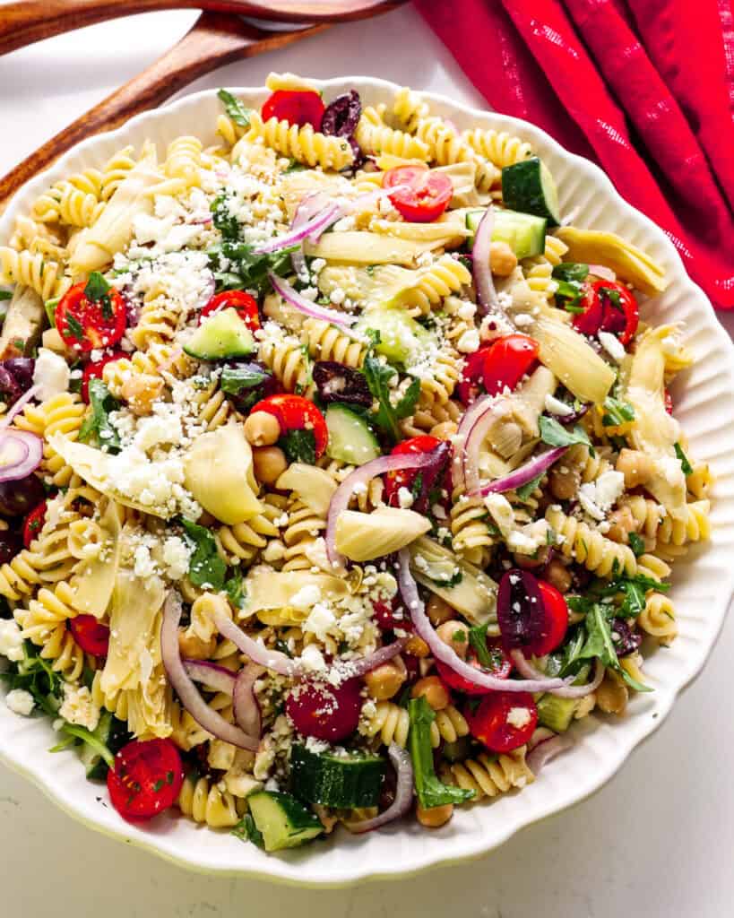 A close up view of Mediterranean pasta salad with Kalamata olives, capers, feta cheese, and artichoke hearts tossed with a zesty red wine vinaigrette.
