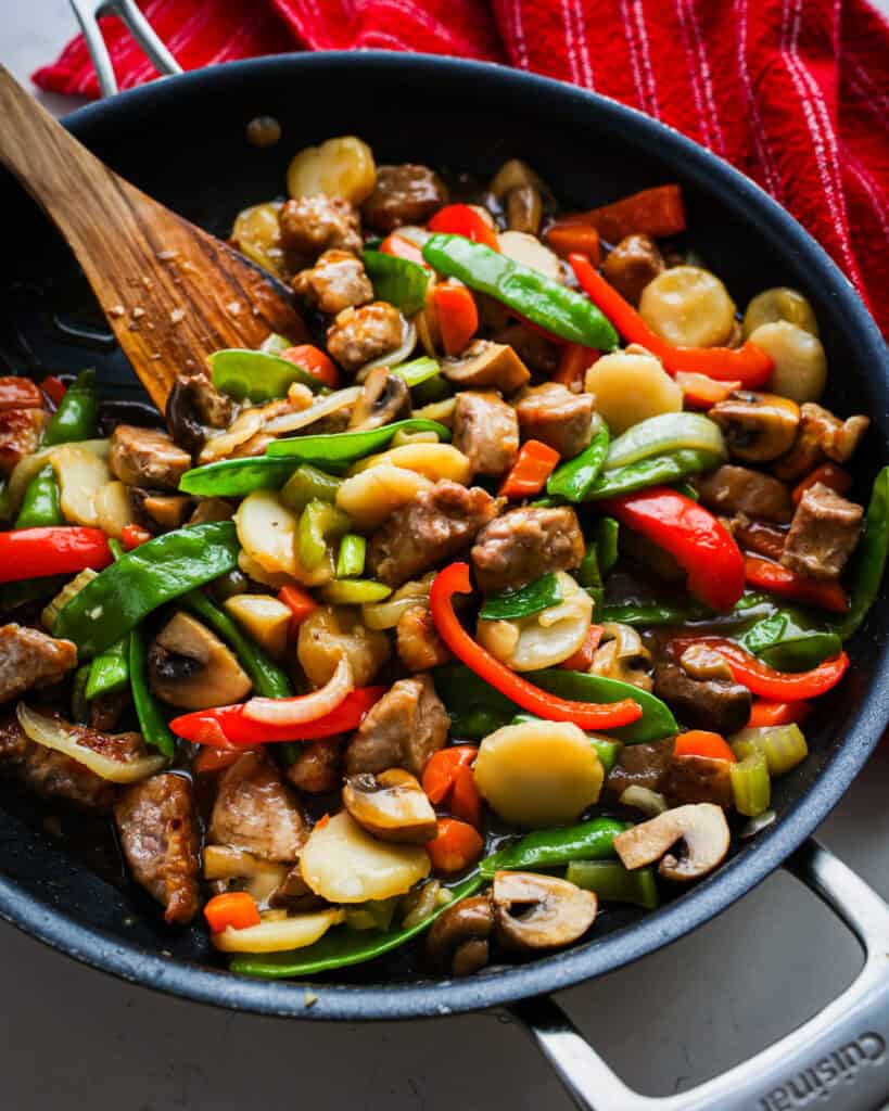 An overhead view of a black skillet full of pork chop suey. 