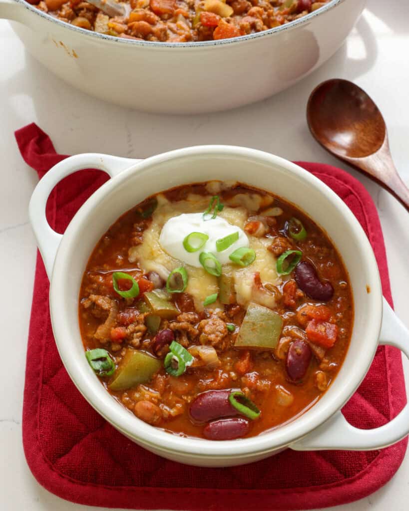 A single serving white crock full of cowboy chili. 