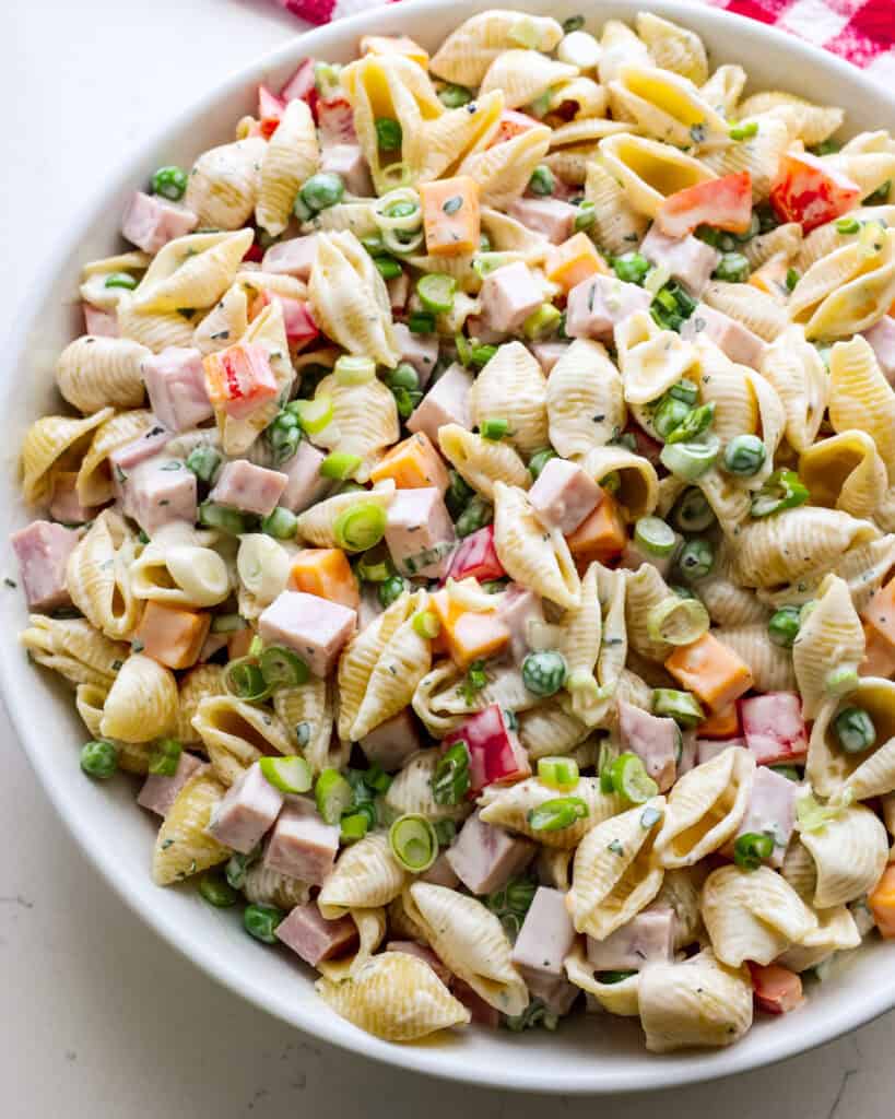 Ham pasta salad with cheddar cheese, red bell pepper, baby peas, and green onions. 