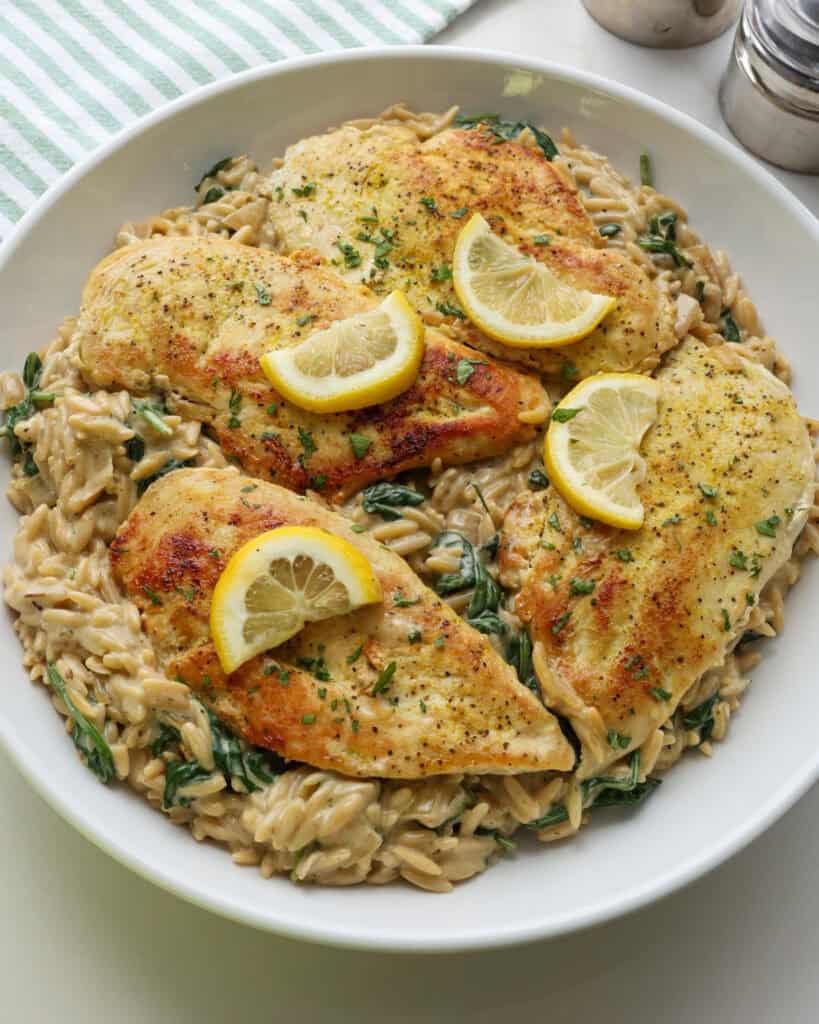 An overhead view of lemon chicken orzo in a large white serving bowl. 