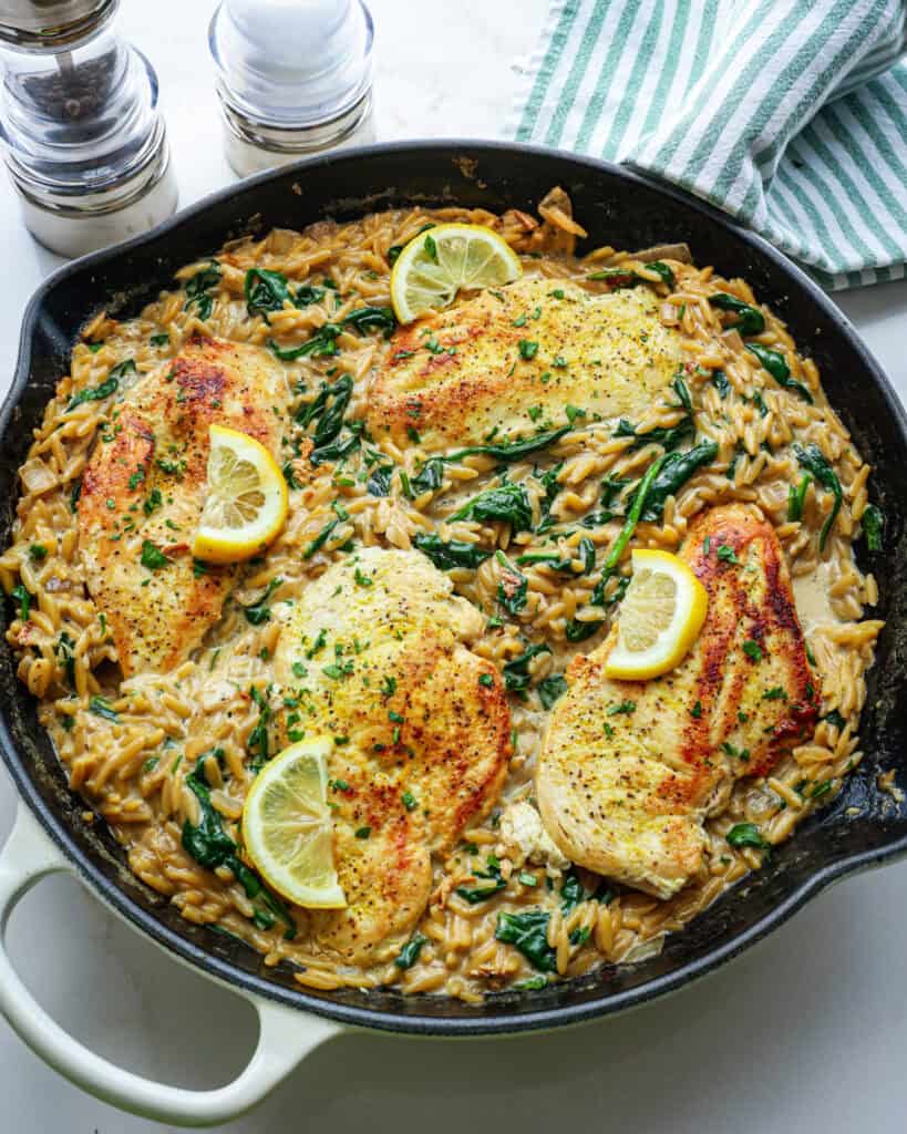 An overhead view of lemon chicken orzo in a large white skillet. 