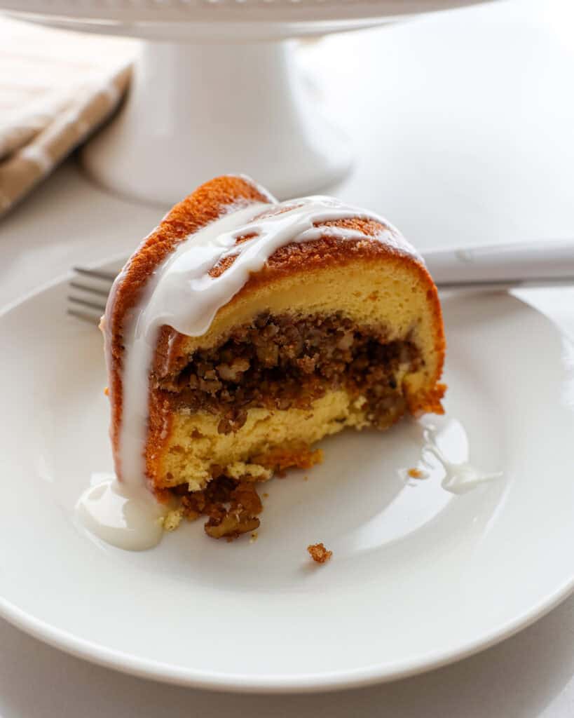 A piece of Sock It To Me Cake on a white plate with a fork in the background.