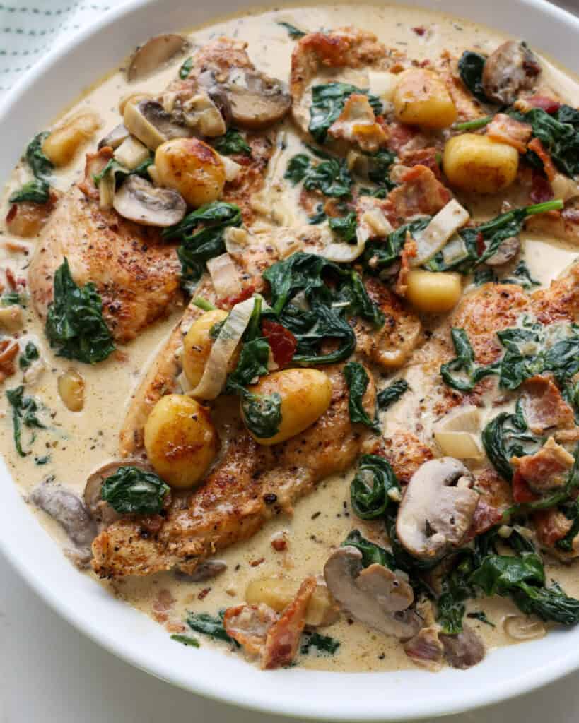 A large white serving bowl full of chicken and gnocchi in Parmesan cream sauce.