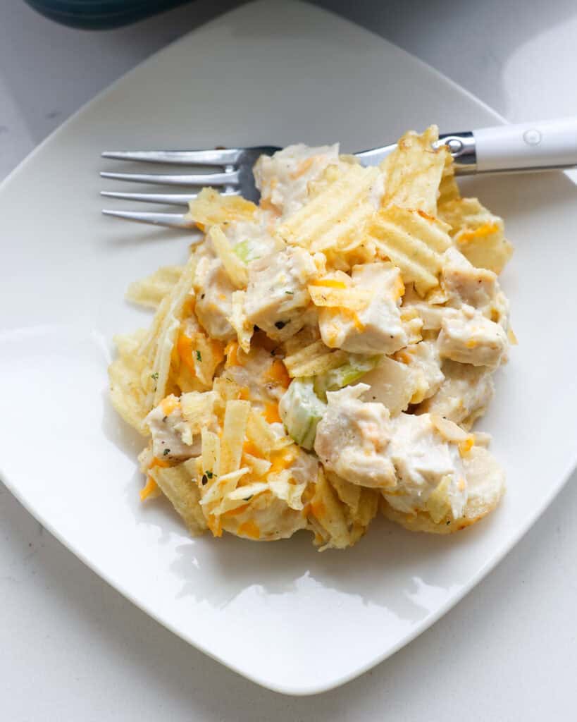 A single serving white plate full of hot chicken salad.