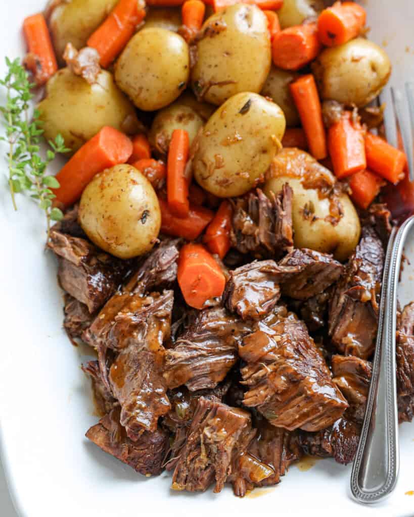 A close up view of instant pot pot roast with gravy, baby yellow potatoes, and carrots.