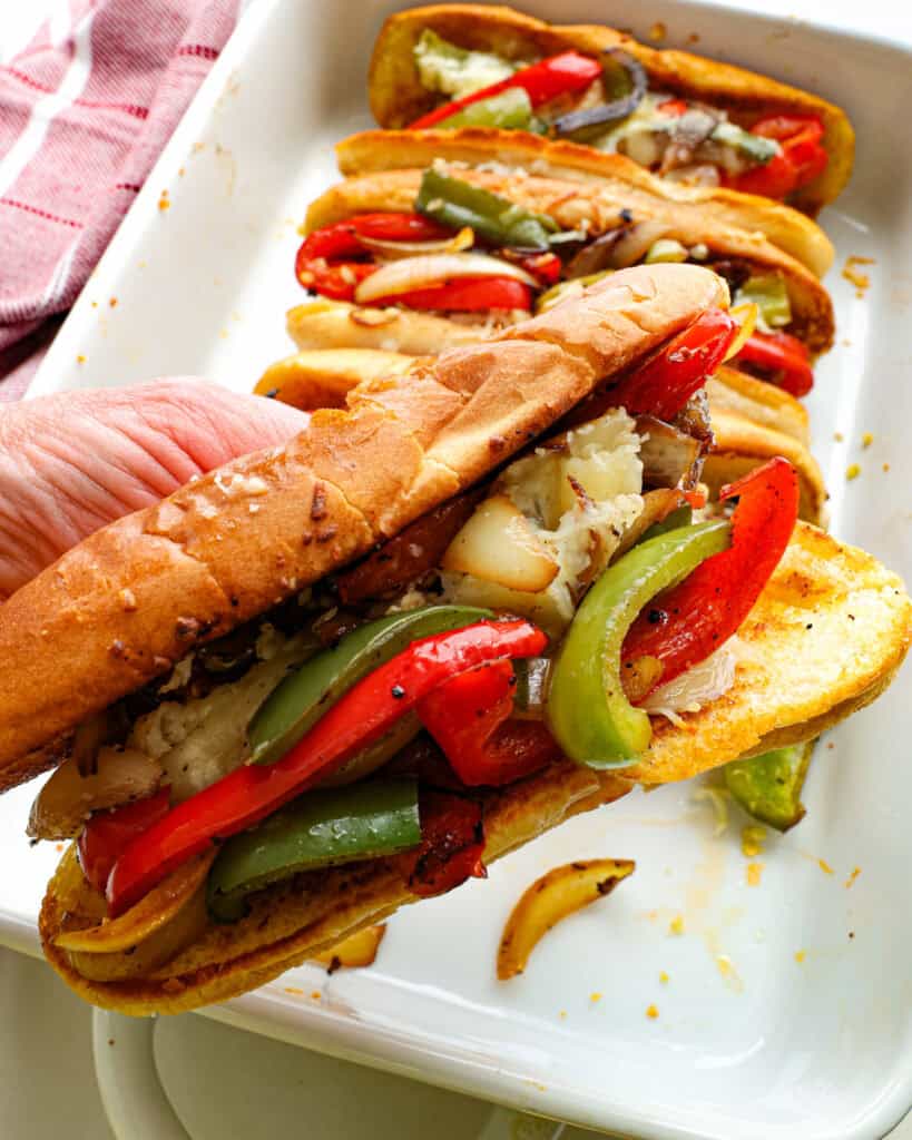 A close up view of an Italian sausage sandwich with bell peppers, and cheese. 