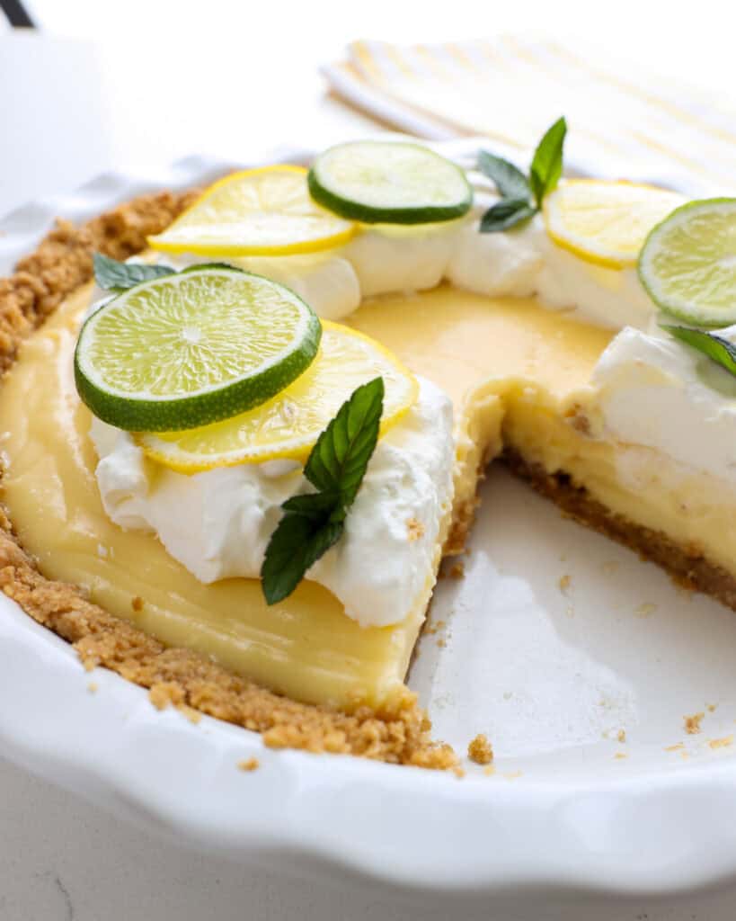 A close up view of a lemon cream pie with a slice out of it.