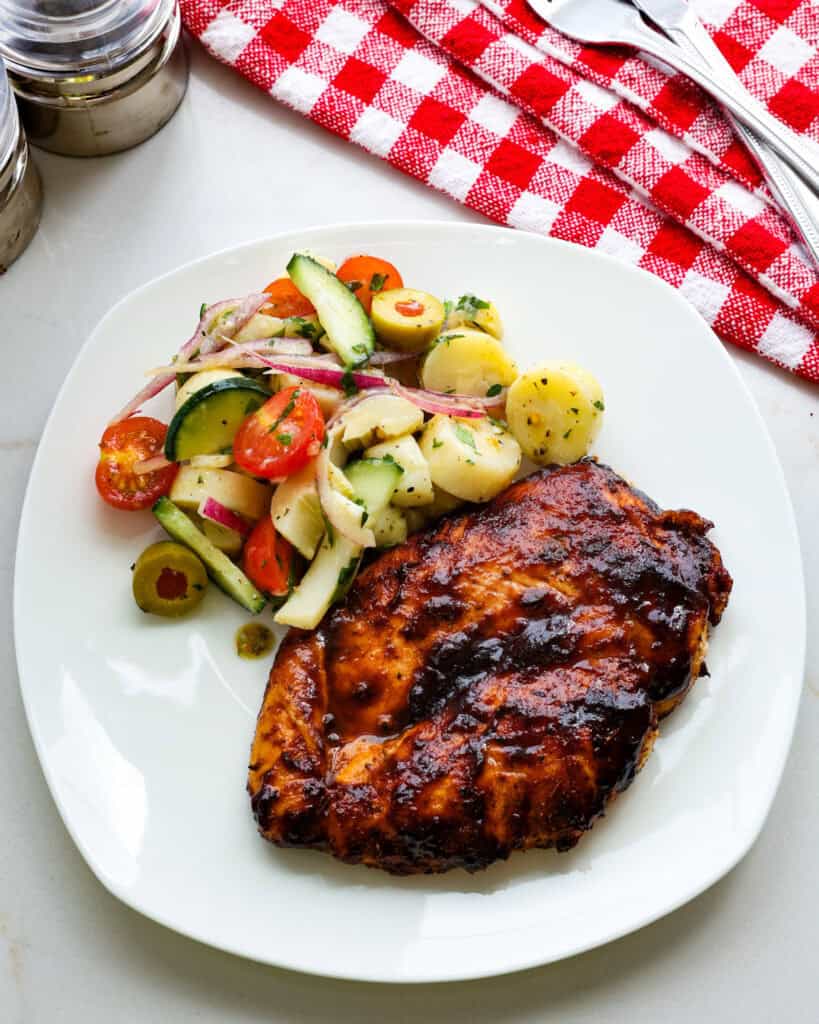 A plate full of oven baked BBQ chicken breast and hearts of palm salad.