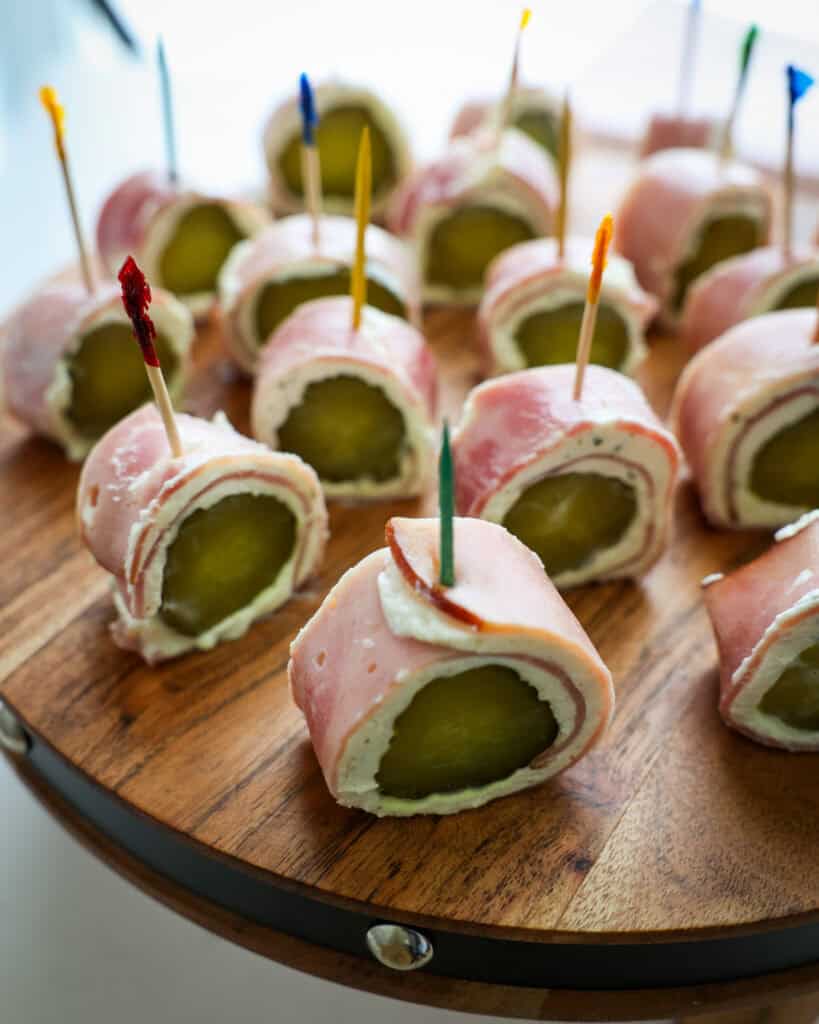 A close up view of a wooden stand full of pickle rolls ups. 