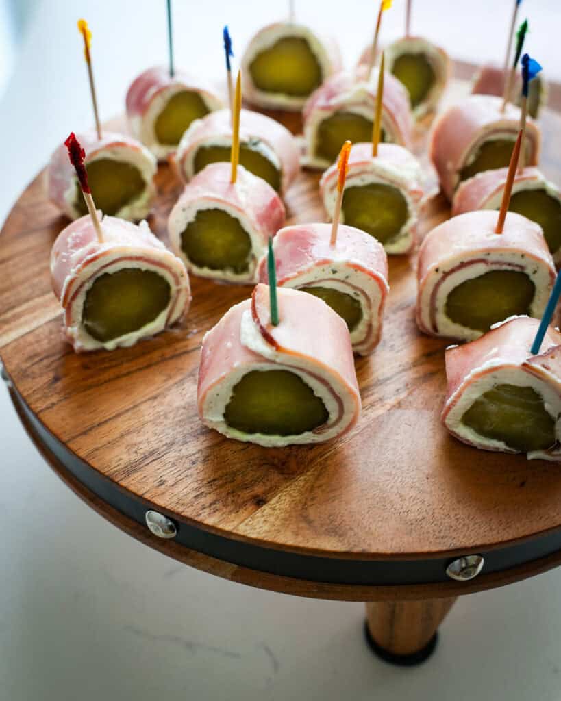 An overhead view of pickle roll ups on a wooden cutting board. 