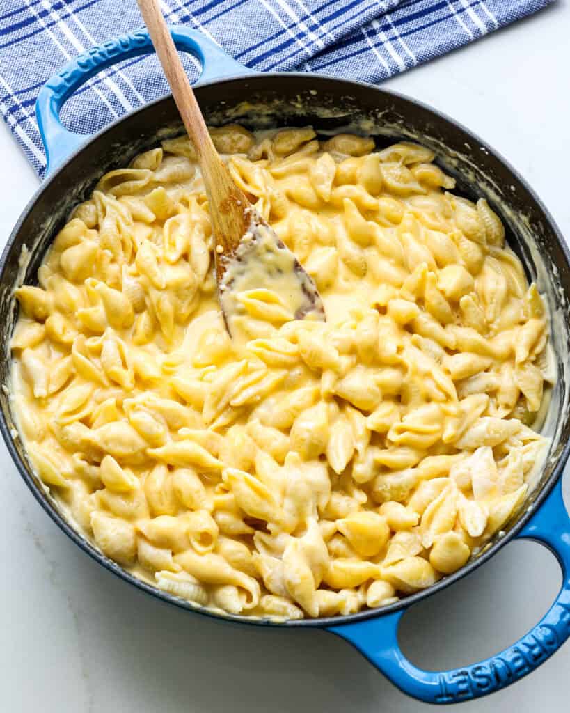 A skillet full of homemade Velveeta mac and cheese with a blue towel in the background.
