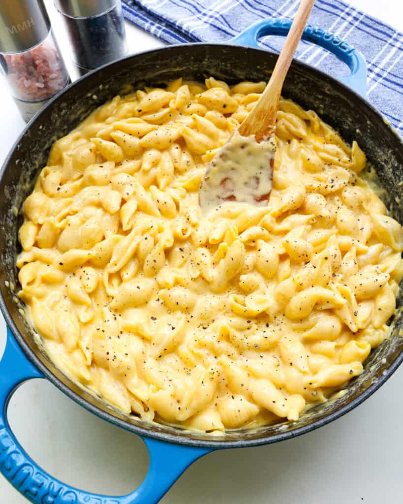 An overhead view of a blue skillet and wooden spoon full of Velveeta mac and cheese.