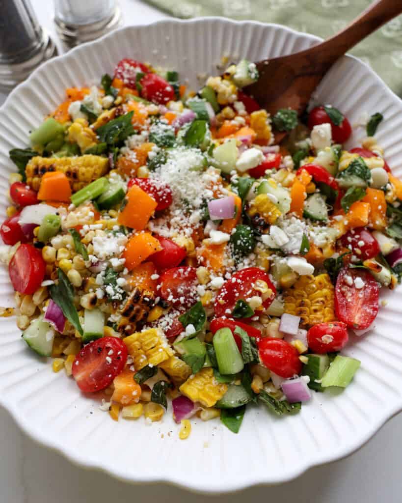 A close up view of grilled corn salad sprinkled with feta cheese. 