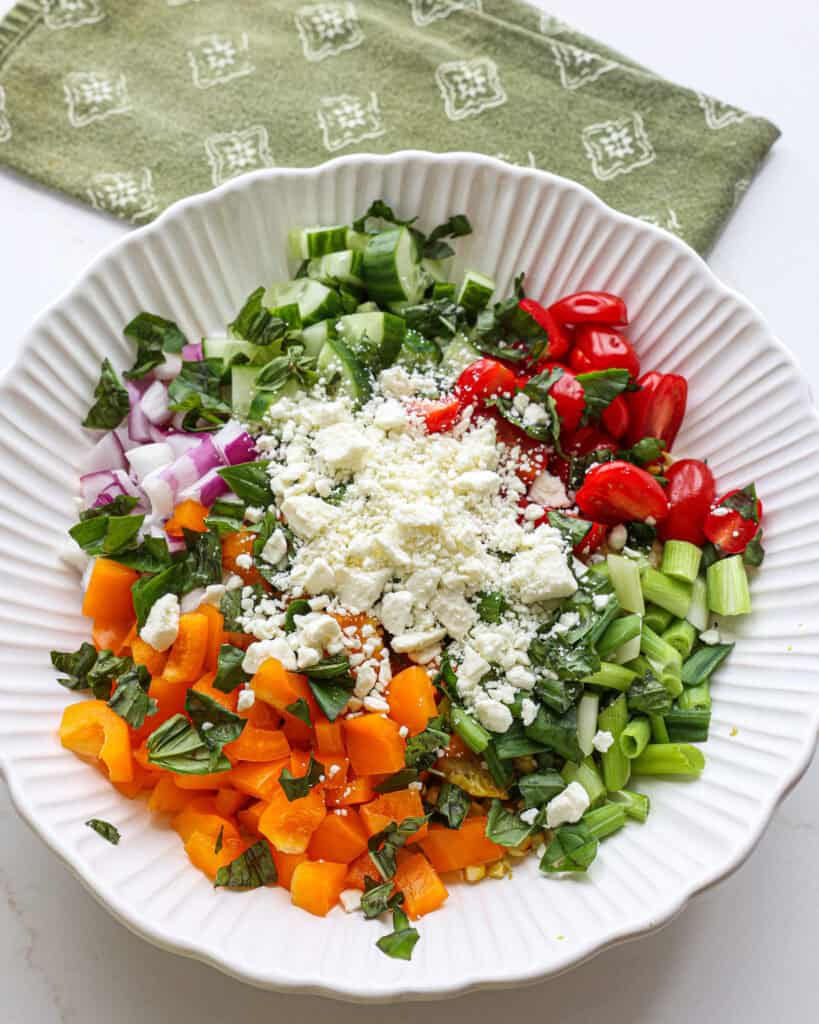 In a large bowl combine the grilled corn, bell pepper, cherry tomatoes, English cucumber, red onion, and green onions. Top with the feta.