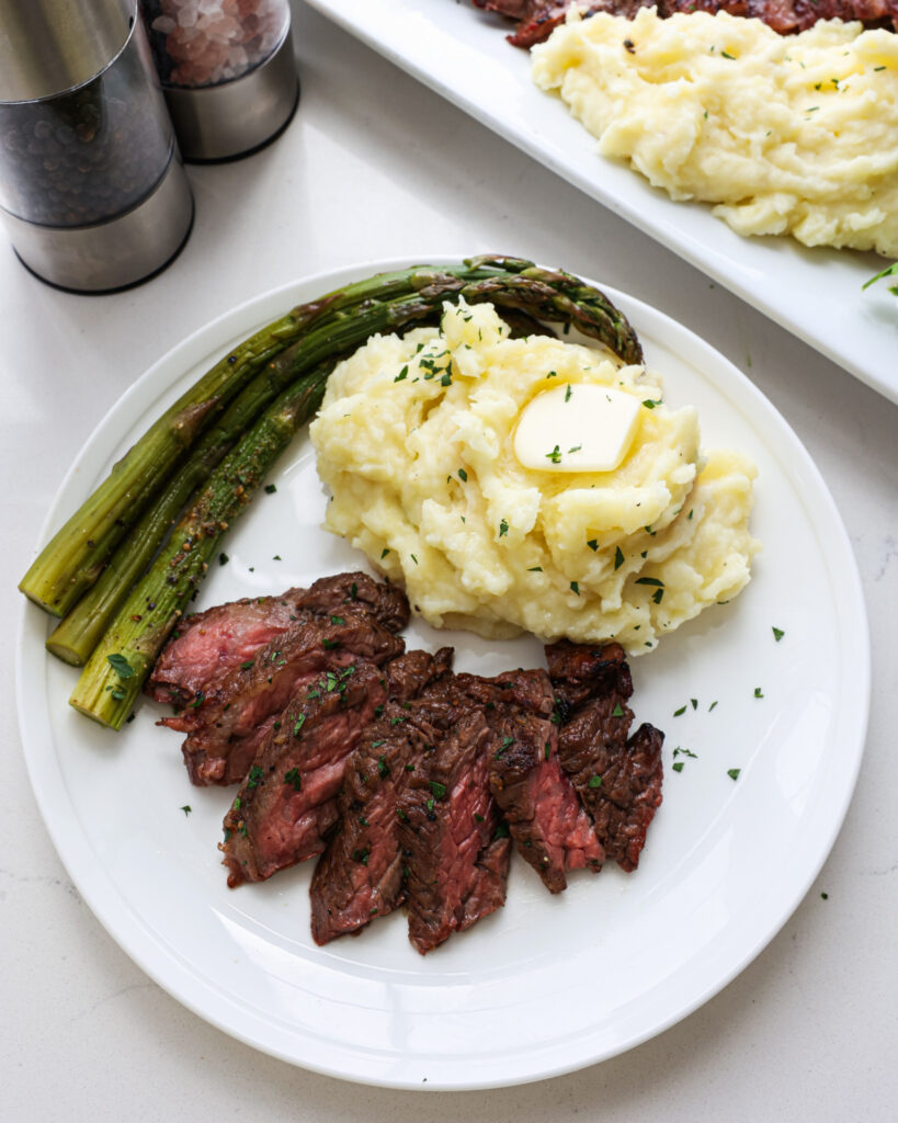 Yukon Gold mashed potatoes on a single serving plate with grilled skirt steak and asparagus.