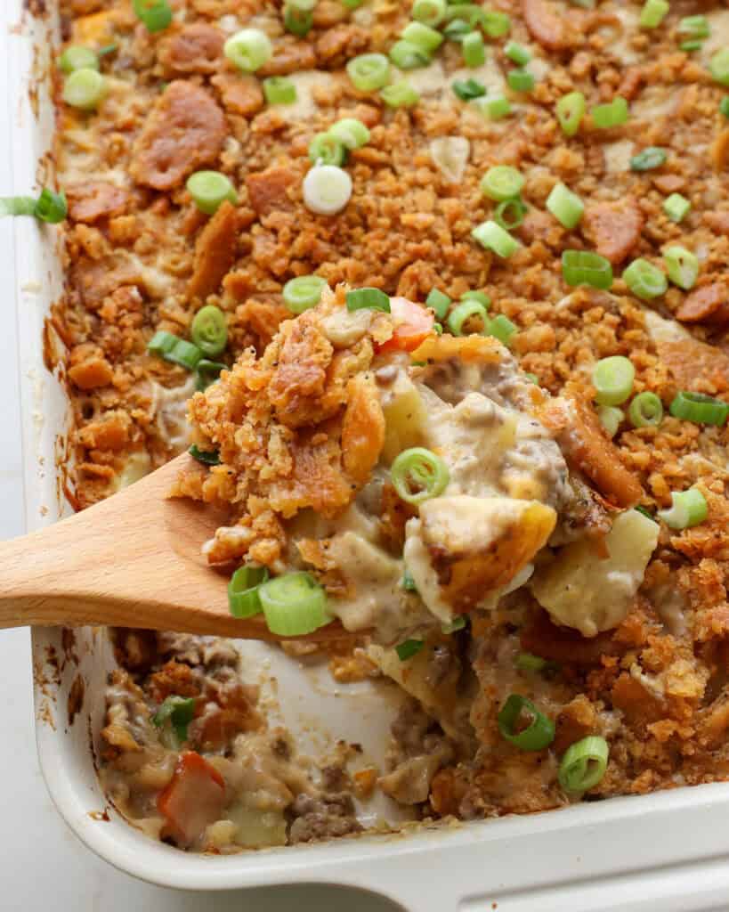 A spoon full of hobo casserole over a 9x13 inch casserole dish full of hobo casserole. 