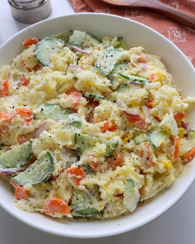 A close up view of Japanese potato salad seasoned with freshly ground black pepper.