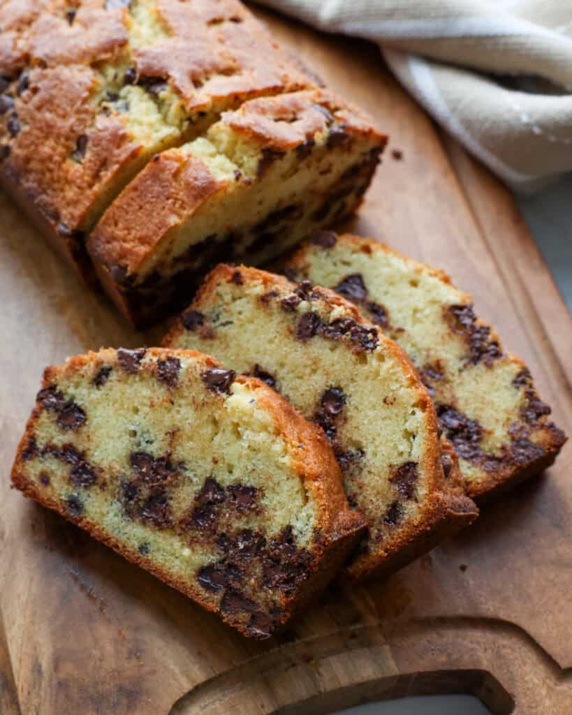 Three slices of chocolate chip pound cake on a cutting board.