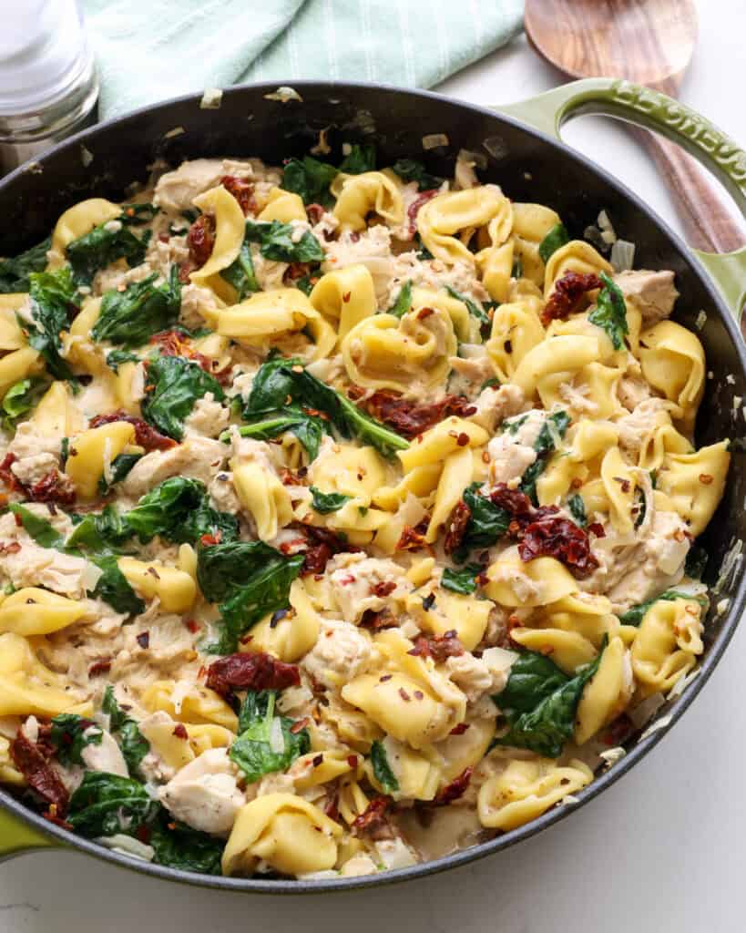 Some of the steps to making creamy chicken tortellini. Stir in the Parmesan cheese and sundried tomatoes. Stir in the cooked chicken and baby spinach. Cook until the spinach wilts.
