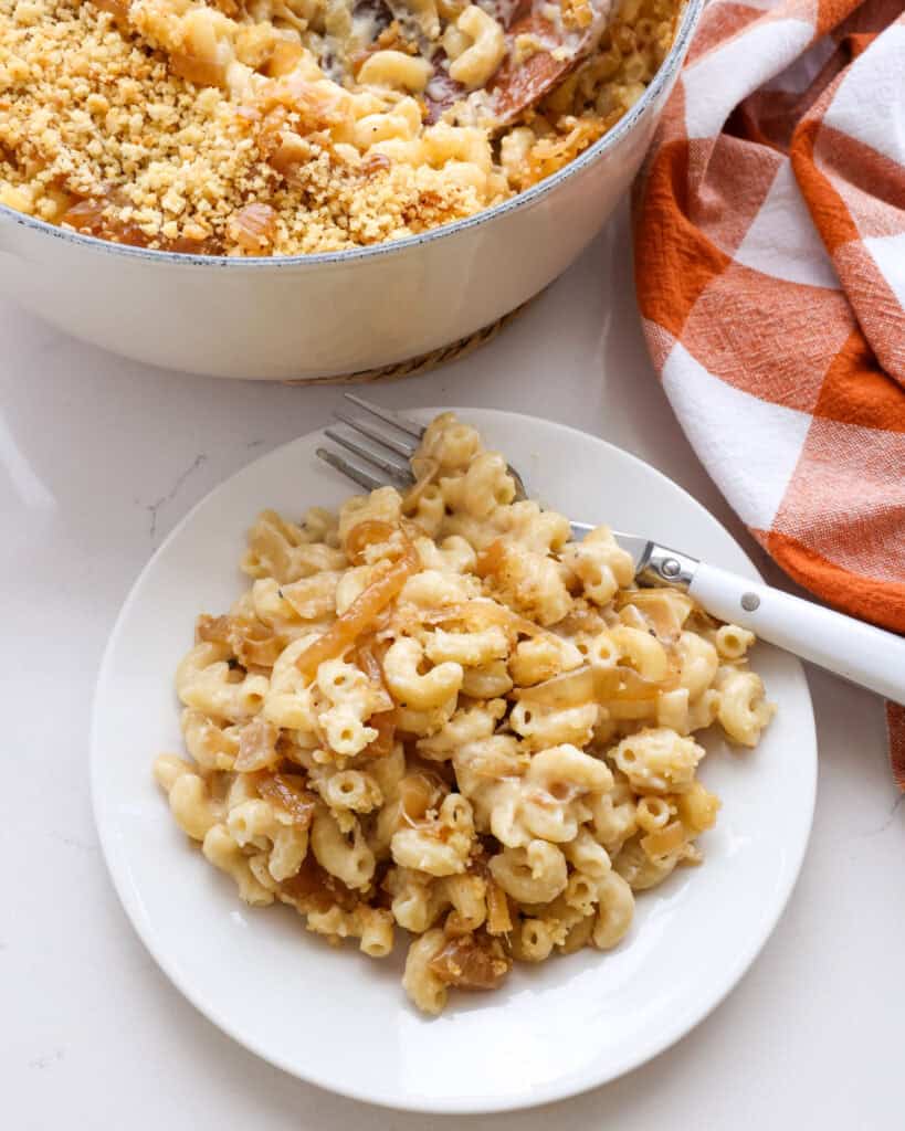 A single serving plate full of french onion mac and cheese with fork on the plate. 