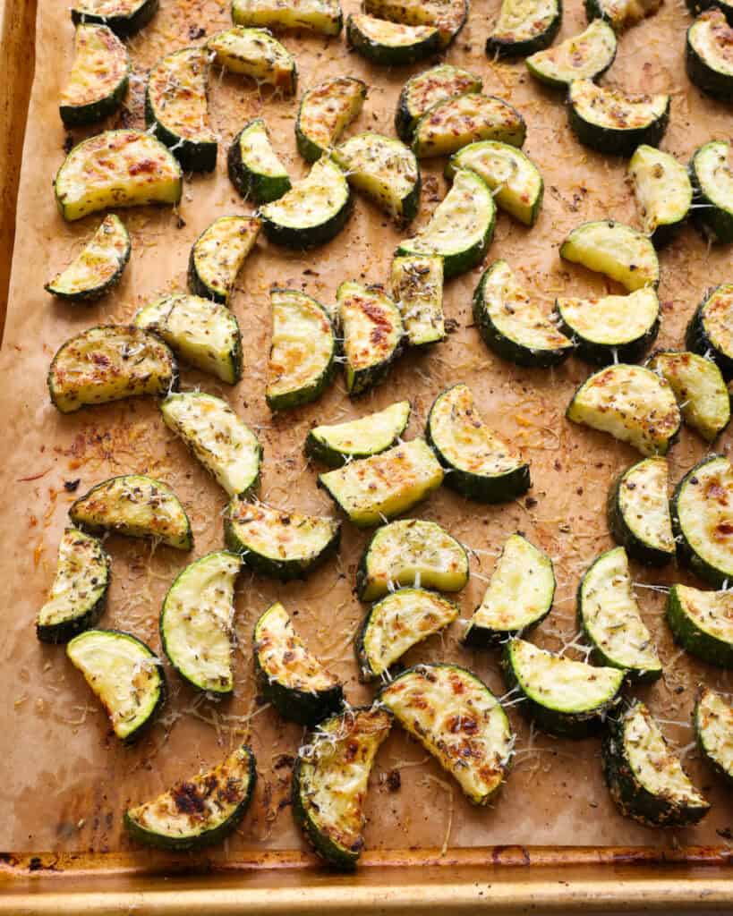 Parmesan roasted zucchini on a parchment paper covered baking sheet.
