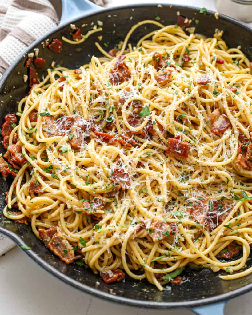 A close up view of spaghetti carbonara with a sprinkle of Parmesan cheese.