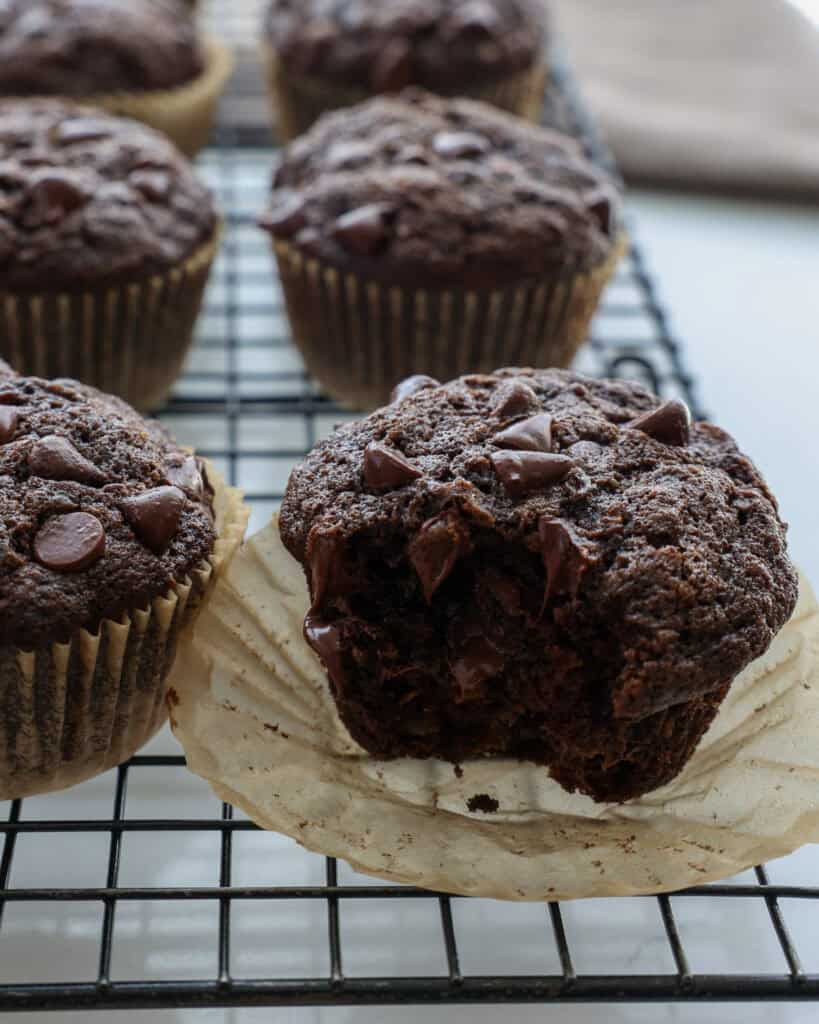 A chocolate zucchini muffin on a wire cooling rack.