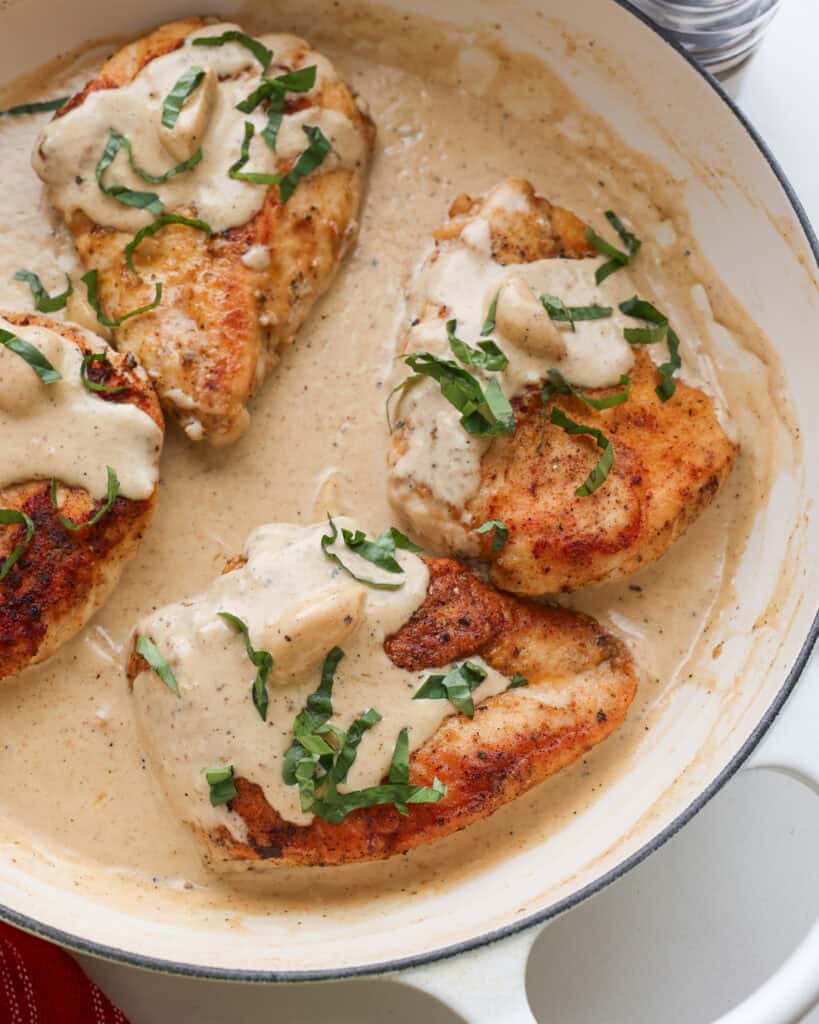 A close up view of creamy garlic chicken in a large white skillet.