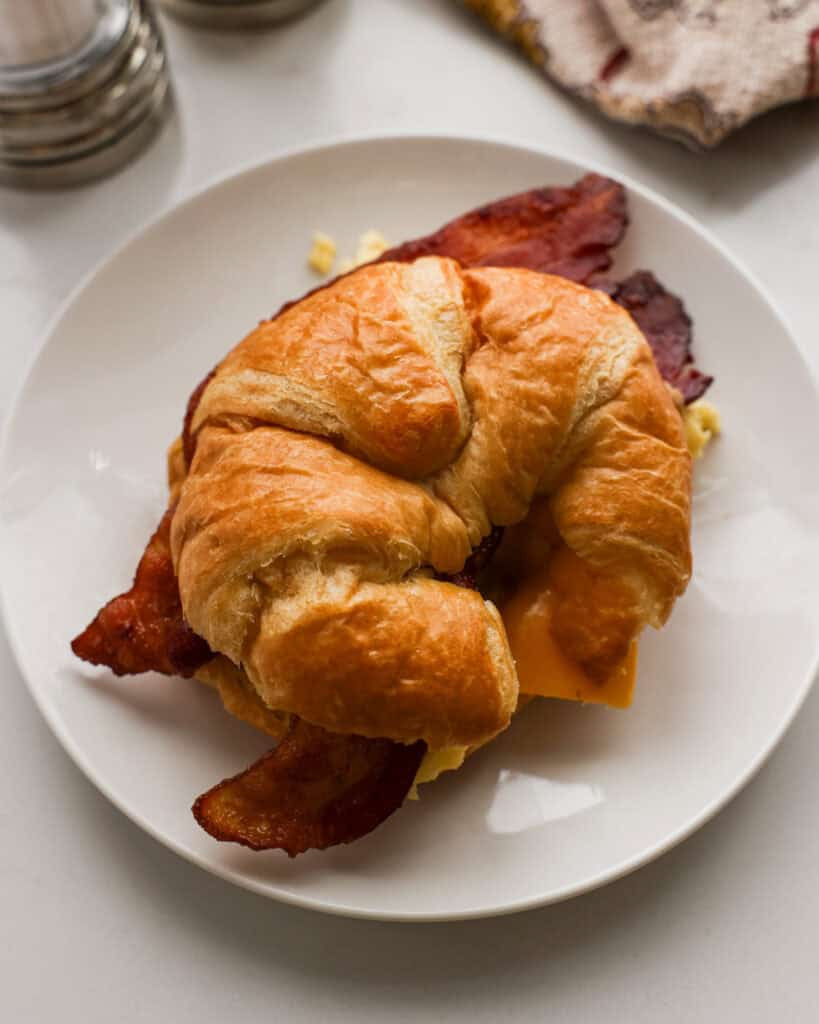 An overhead view of croissant breakfast sandwich with bacon