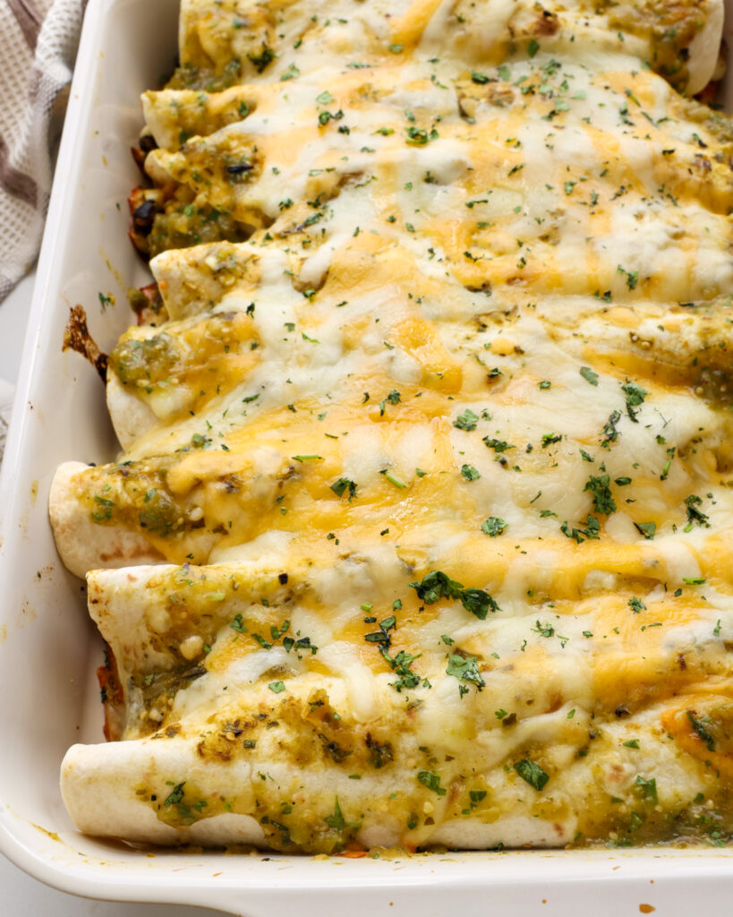 A casserole dish full enchilada verdes with green enchilada sauce.