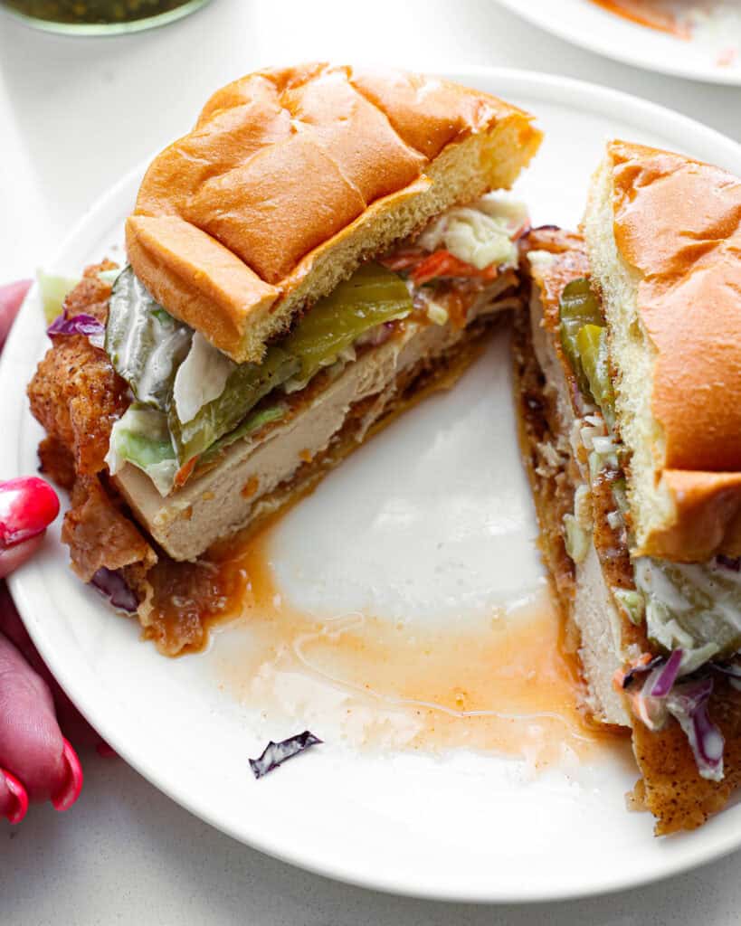 A split hot honey chicken sandwich on a single serving white plate.