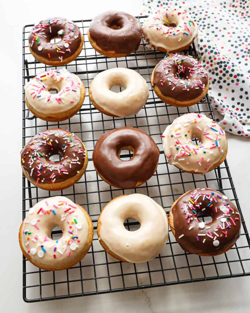 An overhead view of vanilla cake donuts glazed with chocolate and vanilla and topped with sprinkles.